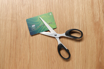 Credit card and scissors on wooden table, top view