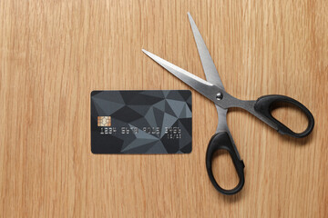 Credit card and scissors on wooden table, top view