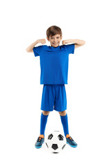 Confident young boy in blue sport outfit posing with classic soccer ball over white background. Looking away