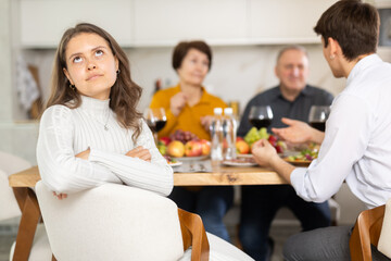 Upset young woman at family holiday table with parents at home. Unpleasant discussion