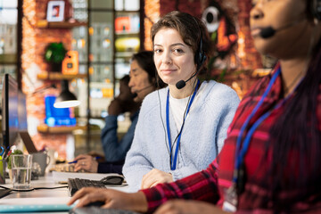 Portrait of cheerful call center manager evaluating company intern performance by judging customers...