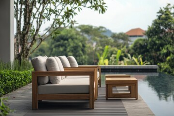 Obraz premium Luxurious outdoor seating area overlooking a serene pool and lush greenery in a tranquil vacation retreat setting during midday