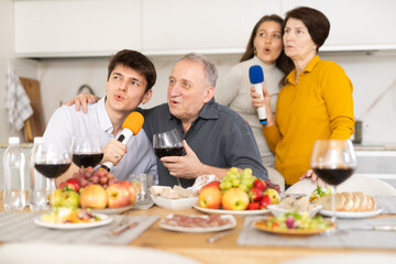 Friendly family with adult children singing karaoke together at home