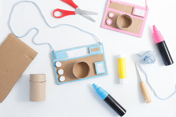 Scene of crafting two cardboard cameras using simple materials like cardboard, scissors, glue,...