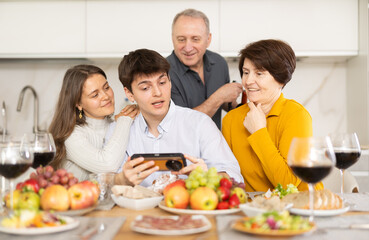 Happy family members looking through photos in light home interior during family holiday