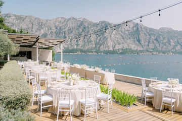Festive tables on wooden floors in the courtyard of the villa overlooking the sea