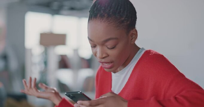 Busy african young woman using mobile phone qhile quarrelling with husband inside apartment interior unboxing packages moving in. Technology.