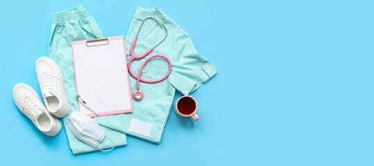 Doctor's uniform with clipboard, shoes, cup of tea and stethoscope on blue background with space for text