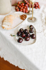 Fresh cherries and bread on a beautifully set dining table in a cozy setting for a summer gathering