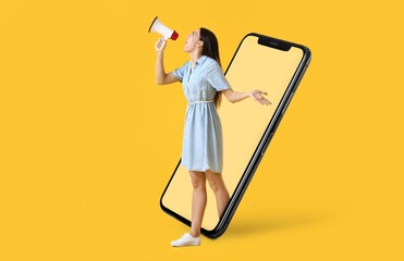 Screaming young woman with megaphone and big mobile phone on yellow background