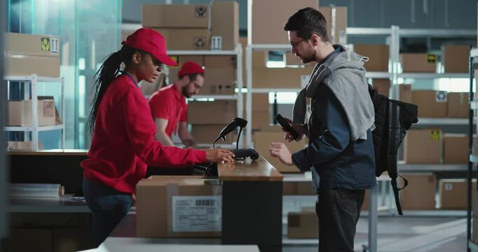 African young polite female worker servicing caucasian customer paying for order receiving cardboard carton parcel delivery box leaving the office.