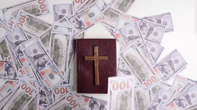 Holy bible with cross resting on scattered us dollar bills