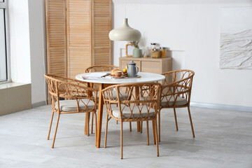Interior of light room with dining table served for breakfast