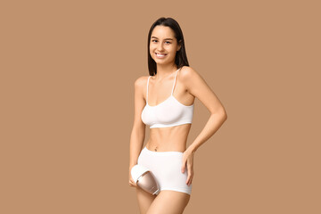 Obraz premium Happy young woman with modern photoepilator on brown background