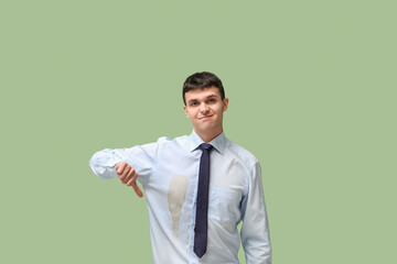 Young businessman with coffee stains on his shirt on green background