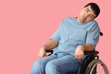 Young man sitting in wheelchair on pink background. National Cerebral Palsy Awareness Month