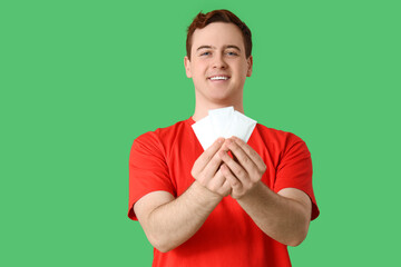 Young man with hygienic tissues on green background