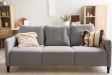 Blurred view of grey sofa with cushions in living room