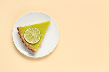 Plate with piece of tasty lime tart on beige background