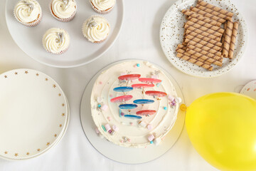 Cake with sweets and balloon for birthday party on white table