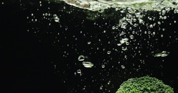 Throwing broccoli into water. Cooking in the kitchen. 