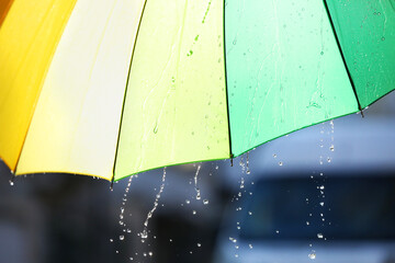 Open bright umbrella under pouring rain outdoors, closeup