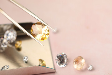 Tweezers with beautiful gemstones on light pink table, selective focus. Space for text