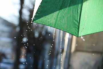 Open green umbrella under pouring rain outdoors, closeup