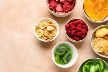 Bowls of different dehydrated fruits and berries on beige background