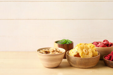 Bowls of different dehydrated fruits and berries on wooden table