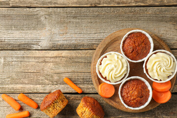 Delicious carrot muffins and fresh vegetables on wooden table, flat lay. Space for text