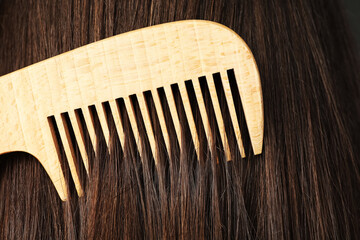 Obraz premium Brushing hair with wooden comb, closeup view