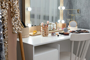 Makeup room. Mirror, dressing table, different beauty products and chair indoors