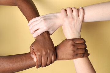 Stop racism. People of different skin colors joining hands on beige background, closeup