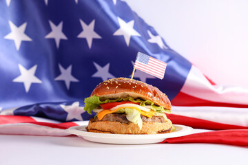Tasty burger with flags of USA on white background. American Independence Day celebration