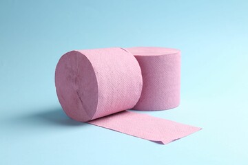 Pink toilet paper rolls on light blue background