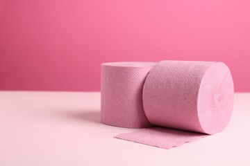 Color toilet paper rolls on pink background. Space for text
