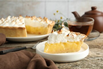 Piece of delicious pie with browned meringue on wooden table, closeup