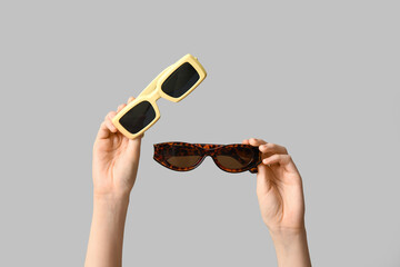 Female hands with different stylish sunglasses on grey background