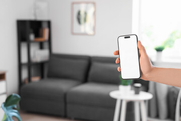 Woman holding mobile phone with blank screen in living room