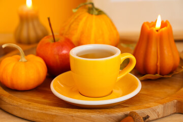 Composition with wooden tray, cup of green tea, candles and pumpkins on table in room, closeup