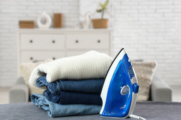 Clean clothes and electric iron on board in room