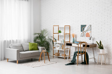 Interior of living room with sofa, workplace and green plants