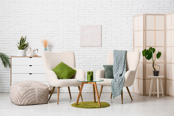 Obraz premium Interior of living room with armchairs and green candles on table