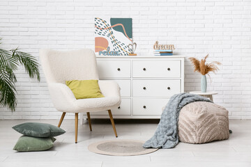 Interior of living room with armchair, pouf and commode