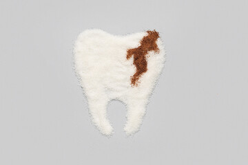 Tooth with caries made of sugar on light background
