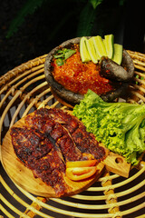 Indonesian's Food. Grilled gourami or Gurame bakar with sambal tomat, slices of cucumber, chilli and lettuce. Selective Focus