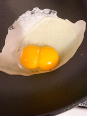Double yolked egg broken open in pan frying. High quality photo