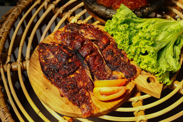 Indonesian's Food. Grilled gourami or Gurame bakar with sambal tomat, slices of cucumber, chilli and lettuce. Selective Focus