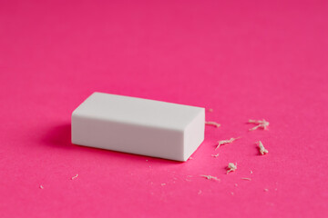 One eraser and scraps on pink background, closeup